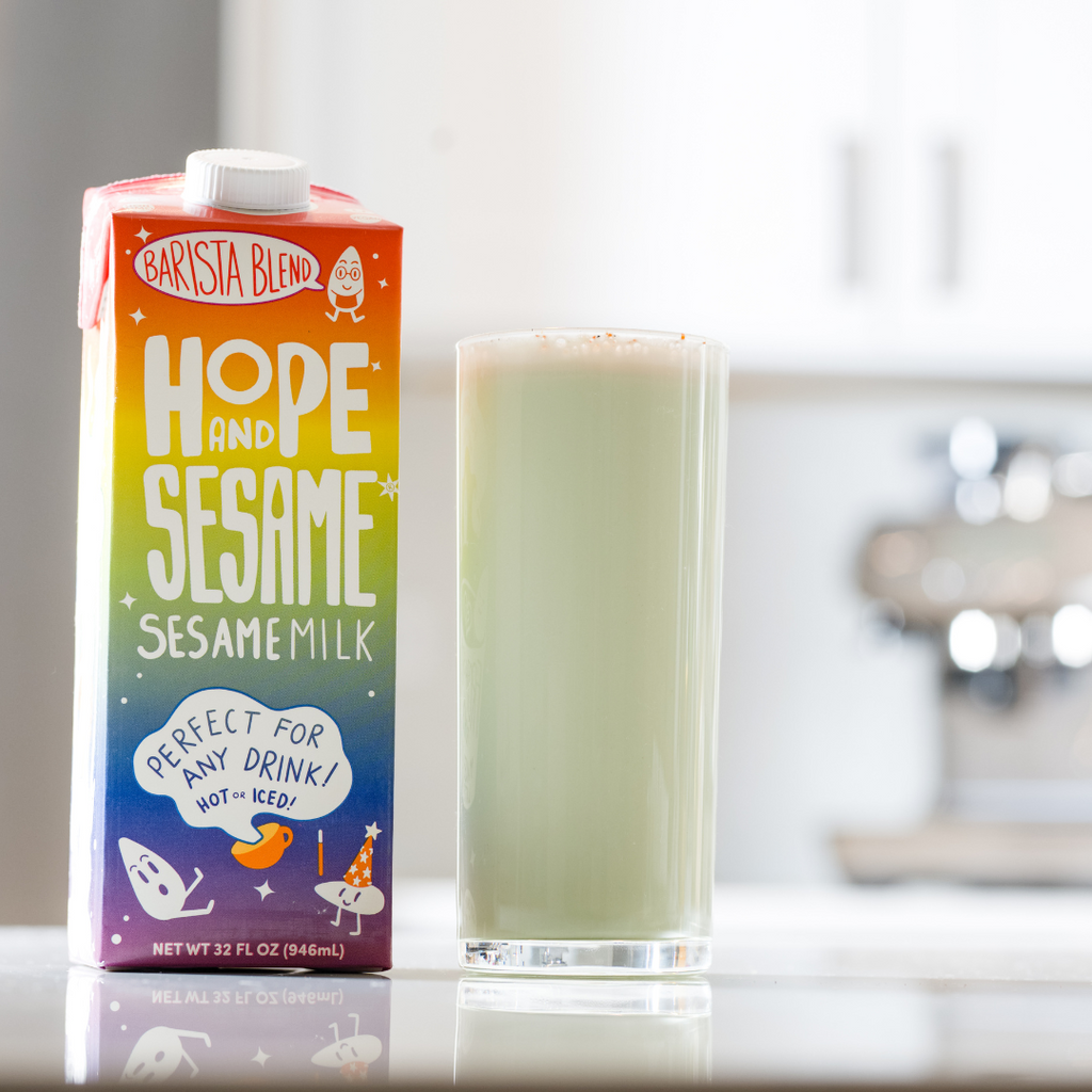 Tall glass of Spiced Honey Dew and Cucumber Refresher with a carton of Hope and Sesame Barista Blend Sesamemilk 