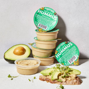 Snack dips by Veggicopia, containers of Veggicopia Creamy Hummus Original stacked with sliced avocado around containers