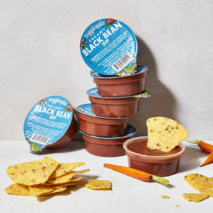 Snack dips by Veggicopia, containers of Veggicopia Creamy Black Bean Dip stacked with chips around an open container